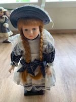 Poupée en porcelaine sur support en bois