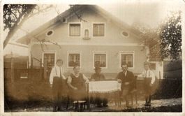 Familie am Tisch im Garten vor Wohnhaus