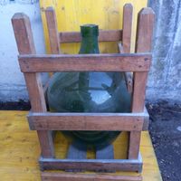 Grosse grüne Glasballonflasche, gebraucht im Holzgestell