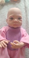 Poupée reborn réaliste en polaire rose et mauve charmante