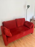 Gemütliches rotes Schlafsofa, perfekt für Gäste.