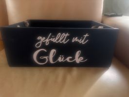 Holzkiste schwarz mit Aufschrift gefüllt mit Glück