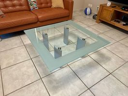 Design-Couchtisch 100×100 cm aus Glas, Alu-Beine auf Rollen