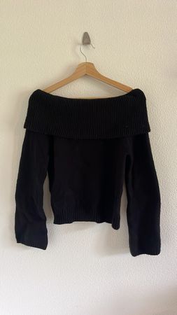 Pull noir épaules découvertes.