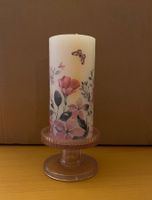 Kerze mit Blumenmotiv und rosa Kerzenständer