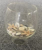 Glasvase mit Meeresdeko und Kerze