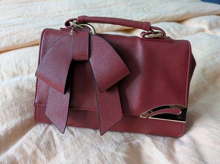 Süsse rote Tasche mit Goldelementen und Schulterriemen