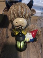 Süsse Highland-Kuh-Figur mit beleuchteter Laterne .