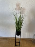 Künstliche Pflanze im schwarzen Metallständer
