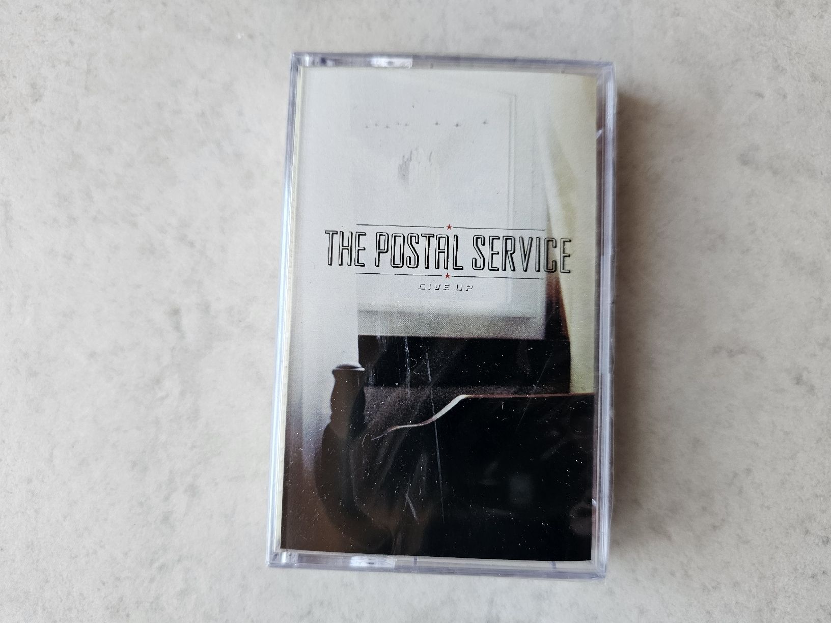 Musicassette: The Postal Service  -  Give Up / Fabrikneu  MC – Nuovo e nell'imballaggio originale da Schneisingen venduto da backstore24