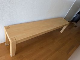 Sitzbank aus hellem Holz mit Gebrauchsspuren