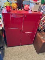 1 rotes Sideboard, hoch auf Rollen. 2 Schubladen, 2 Türli