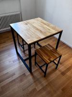Moderner Holztisch mit Metallgestell und zwei Hockern