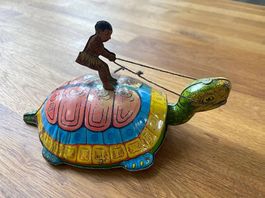 Blechspielzeug "Junge reitet auf einer Schildkröte