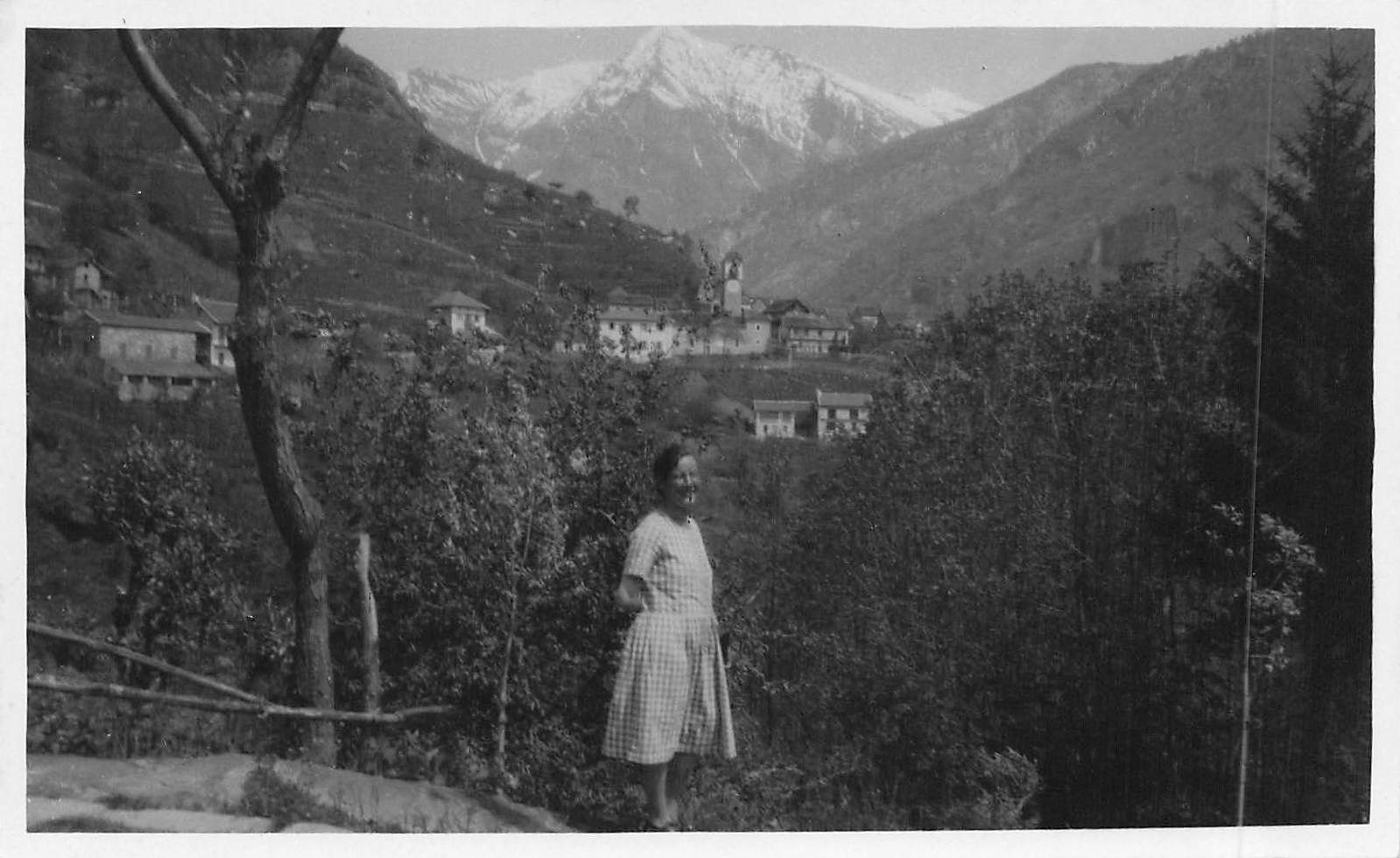 Cartoline postali: TI Donna con panorama alpino e villaggio – Usato da Biasca venduto da Blenio71