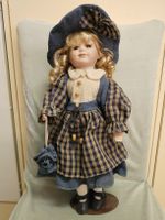 Porzellanpuppe mit blau-beigem Kleid