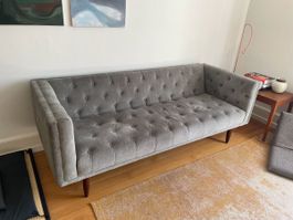 Graues Sofa mit Knöpfen, ideal für stylishe Wohnung.