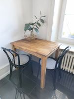 Tisch aus Holz mit zwei schwarzen Stühlen