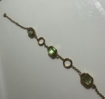 Armband mit gruenen Steinen und goldfarbenen Ringen