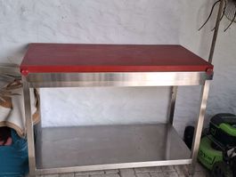 Robuster Arbeitstisch mit Edelstahlgestell und roter Platte