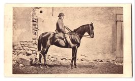 Fotografie Mann auf Pferd vor einer Haus
