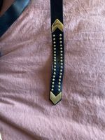 Ceinture en cuir noire et dorée.