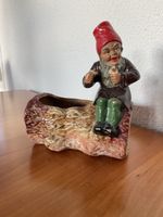 Antiker Gartenzwerg auf Baumstamm