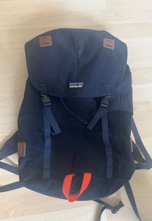 Patagonia: dunkelblauer Rucksack mit orangem Griff