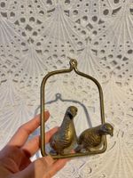 Zwei Messing Vögel sitzen auf einer Schaukel