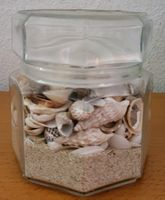 Glasvase mit Sand und Muscheln 