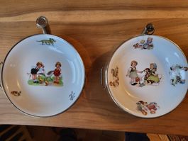 Ein Paar Kinderteller mit Kinderszenen und mit Wasserwärmer.