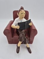 Tintin assis lisant le journal