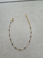 Goldiges Armband mit schwarzen Perlen