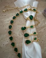Ensemble de bijoux dorés avec pierres vertes émeraude.