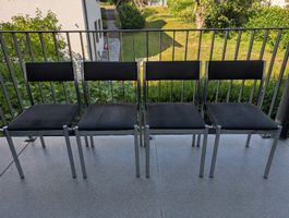 4 schwarze Stühle mit Chrombeinen