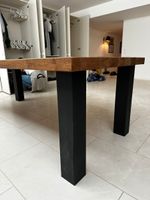 massiver Holztisch mit schwarzen Metallbeinen