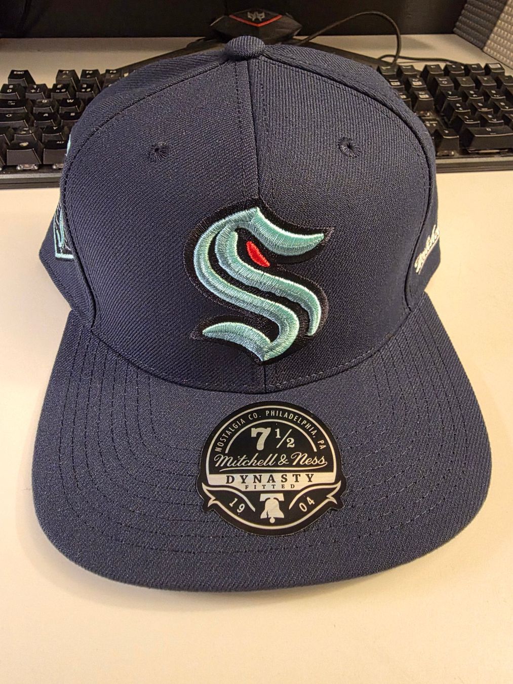 Mitchell & Ness Copricapi, berretti & cappellini: Cap Mitchell & Ness Dynasty Fitted 7 1/2 Seattle Kraken – Nuovo e nell'imballaggio originale da Mörigen venduto da Gadgeteer