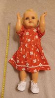 Alte Spielzeugpuppe mit rotem Blumenkleid gebraucht