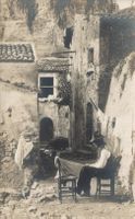 Alte Fotografie: Mann sitzt auf Stuhl, malerische Gasse.
