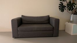 Graues 2er-Sofa mit Kissen von IKEA mit Bettfunktion