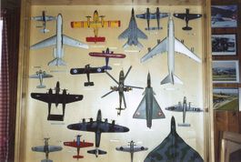 Collection avions miniatures dans vitrine d'exposition bois.