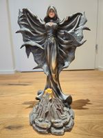 Elfenfigur im Rabengewand hinter Vulkan stehend