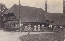 Altes Berner-Bauernhaus mit Bauerfamilie davor.
