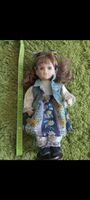 Porzellanpuppe mit braunen Locken und blauem Kleid