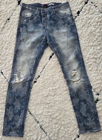 Eine Jeans mit Camouflage-Muster und Destroyed-Elementen.