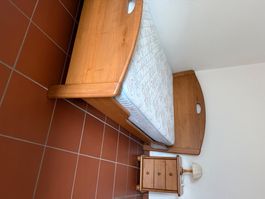Lit en bois massif avec table de chevet et lampe.