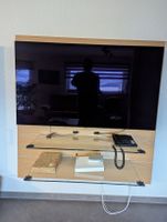 Meuble TV mural  en bois clair et verre.