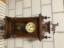 Orologio da parete antico in legno con pendolo.