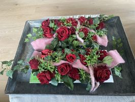 Blumengesteck mit roten, künstlichen Rosen und Efeu