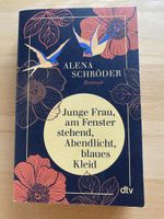 Junge Frau am Fenster stehend, Abendlicht, blaues Kleid